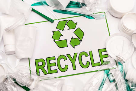 top view of recycle card and plastic rubbish scattered on white background