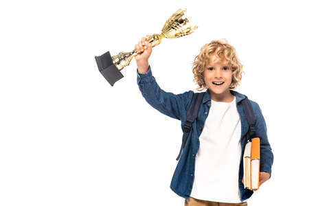 blonde schoolboy holding golden trophy and books isolated on white