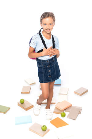 schoolgirl with backpack standing near apples and books isolated on whiteの写真素材