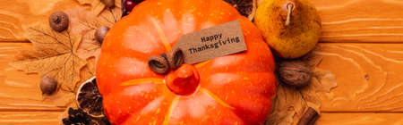 top view of pumpkin with autumnal decoration and happy thanksgiving card on wooden background,...