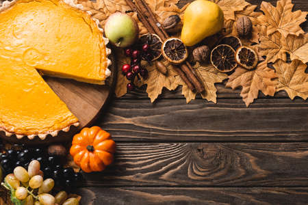 top view of autumnal decoration and pumpkin pie on brown wooden backgroundの写真素材