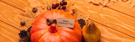 top view of pumpkin with autumnal decoration and happy thanksgiving card on wooden background, panoramic shotの写真素材
