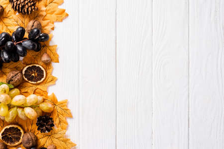 top view of autumnal decoration and grapes on white wooden background