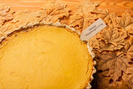 thanksgiving pumpkin pie with autumnal foliage on wooden background