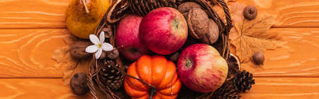 top view of wicker basket with autumnal harvest on wooden background, panoramic shotの写真素材