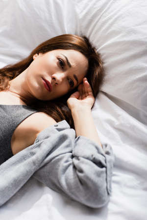 high angle view of upset woman lying on bed and looking away