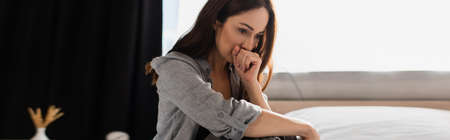 panoramic concept of depressed brunette woman covering mouth at home