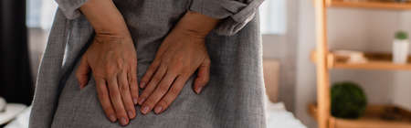 panoramic crop of woman suffering from back pain at homeの写真素材
