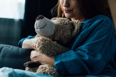 cropped view of depressed brunette woman holding teddy bearの写真素材