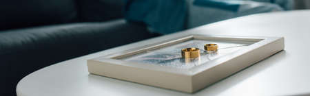 panoramic crop of golden rings on photo frame with broken glass, divorce concept