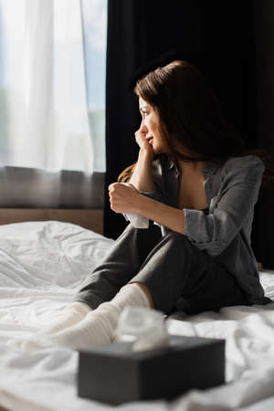 selective focus of depressed woman sitting on bed near tissue box