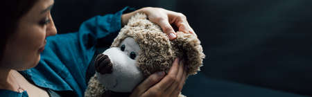 horizontal image of depressed woman holding teddy bear