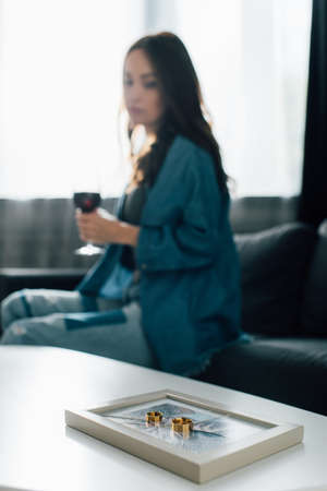 selective focus of golden rings on photo frame with broken glass near brunette woman, divorce conceptの写真素材