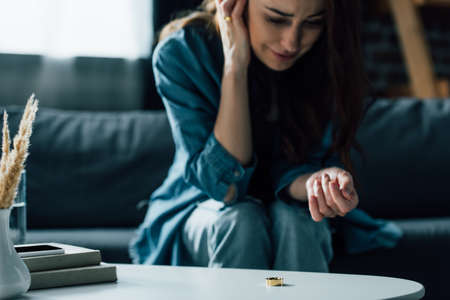 selective focus of golden ring on coffee table near upset woman, divorce conceptの写真素材