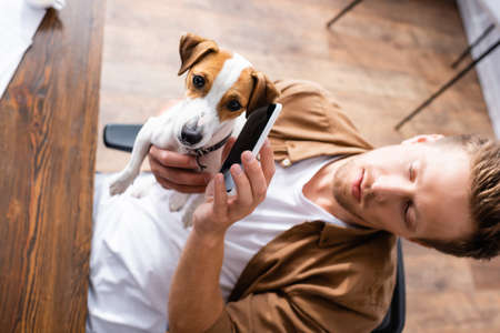high angle view of businessman holding cellphone near ear of jack russell terrier dogの写真素材
