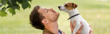 horizontal concept of young man holding jack russell terrier dog with brown spots on headの写真素材