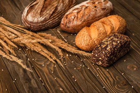 fresh baked bread loaves with spikelets on wooden surfaceの写真素材