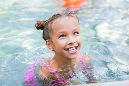 excited girl looking away while swimming in poolの写真素材