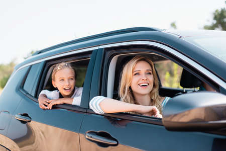 Selective focus of excited mother and kid looking away while traveling in autoの写真素材