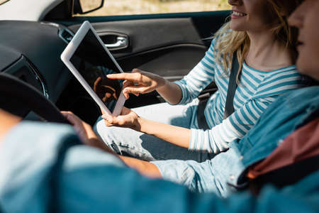 Cropped view of woman pointing at digital tablet while husband driving car