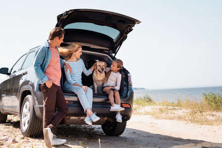 Selective focus of family with golden retriever traveling on car on beachの写真素材