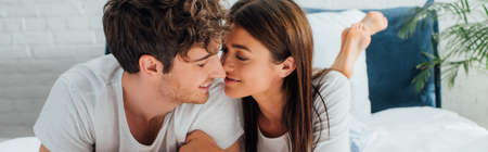 Panoramic shot of young couple lying on bed at morning