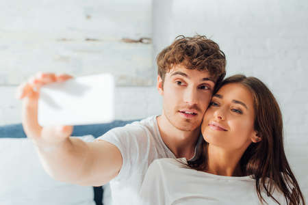 Selective focus of couple taking selfie at home