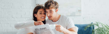 Panoramic shot of woman looking at newspaper near boyfriend with cup of coffee at homeの写真素材