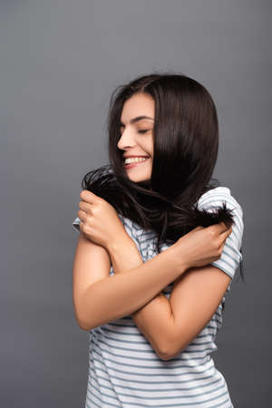 brunette long haired woman with closed eyes smiling isolated on blackの写真素材