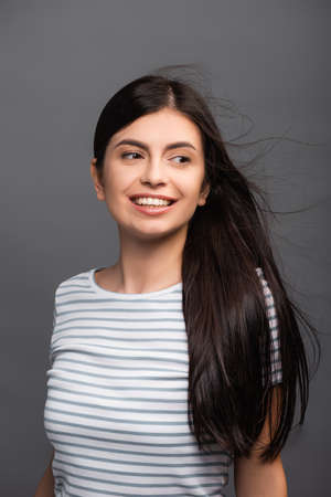 wind blowing through hair of brunette woman isolated on black