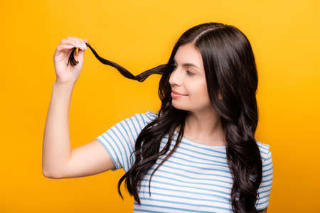 brunette woman looking at curl isolated on yellowの写真素材