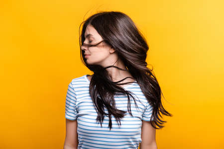brunette woman with curls waning hair isolated on yellowの写真素材