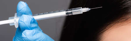 close up view of brunette woman having scalp mesotherapy isolated on black, panoramic shotの写真素材