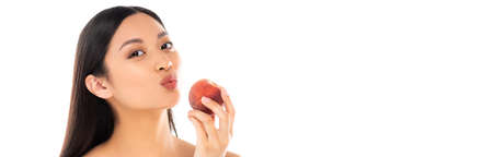 panoramic concept of asian woman making duck face while holding juicy peach isolated on whiteの写真素材