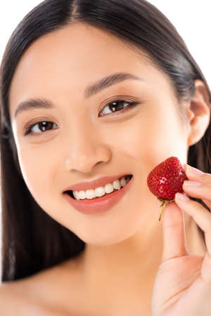 selective focus of asian woman holding ripe strawberry near face isolated on whiteの写真素材