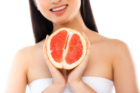 cropped view of woman holding half of juicy grapefruit isolated on whiteの写真素材
