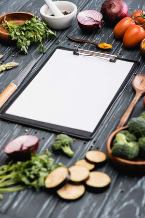 selective focus of blank clipboard near spices and vegetables on wooden surfaceの写真素材