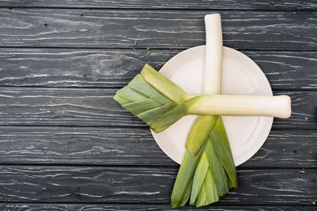 top view of fresh green leek on plate on wooden surfaceの写真素材