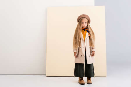 fashionable blonde girl in autumn outfit on beige and white backgroundの写真素材