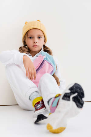 selective focus of blonde girl in sportswear sitting near white wallの写真素材