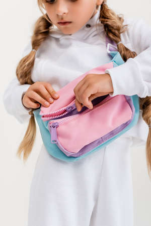 cropped view of blonde girl in sportswear unfastening belt bag isolated on whiteの写真素材