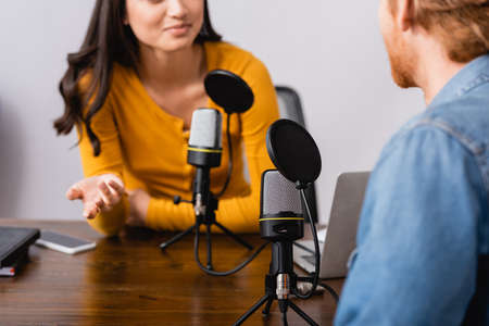 cropped view of radio host gesturing while interviewing man in studioの写真素材