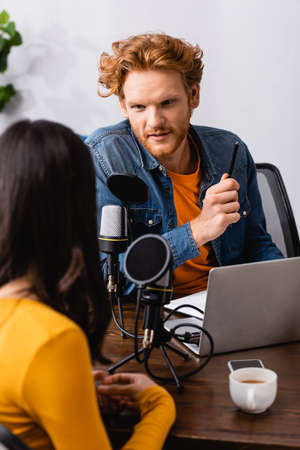 back view of brunette woman near young redhead interviewer in radio studioの写真素材