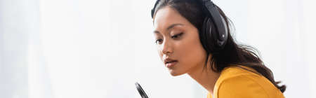 website header of pensive asian announcer in wireless headphones working in radio studioの写真素材