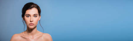 horizontal image of young and naked woman looking at camera isolated on blueの写真素材