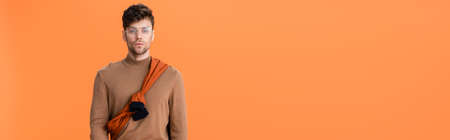 horizontal image of trendy man in autumn outfit and glasses isolated on orangeの写真素材