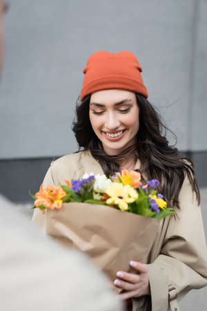 selective focus of young woman looking at bouquet of flowersの写真素材
