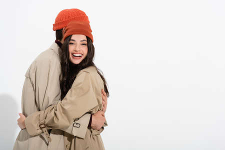 trendy woman in beanie hat hugging man on whiteの写真素材