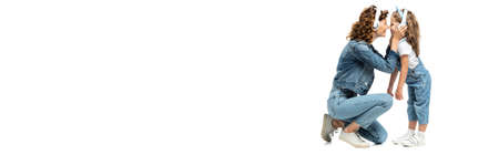 side view of mother and daughter in denim outfits listening music in headphones face to face isolated on white, panoramic shotの写真素材