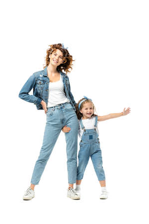 daughter in denim outfit hugging mother leg with outstretched hand isolated on whiteの写真素材